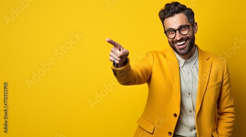 excited young man in yellow jacket pointing with finger on yellow background