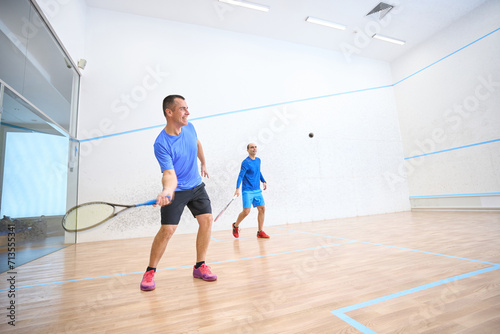 Sporty men having fun playing squash mixing recreation with fitness