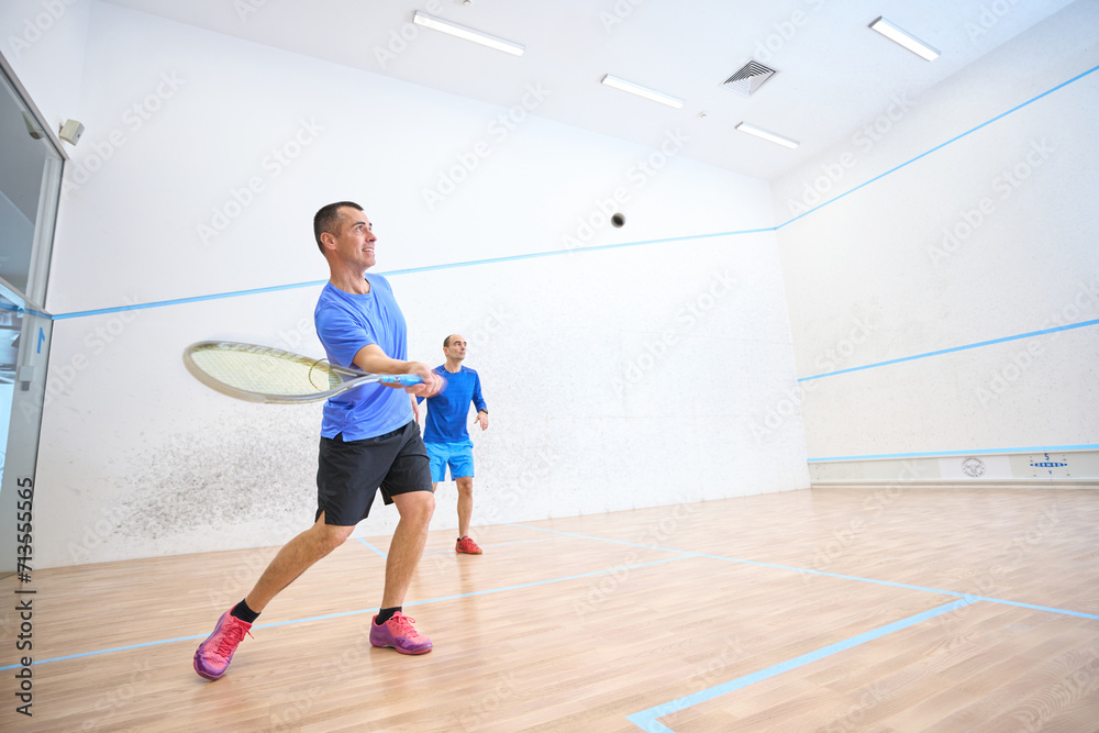 Active men working out engaging in friendly squash matches