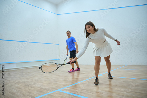 Athletic man and woman improving squash techniques