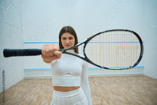 Sporty woman on squash court showing racket © Viacheslav Yakobchuk