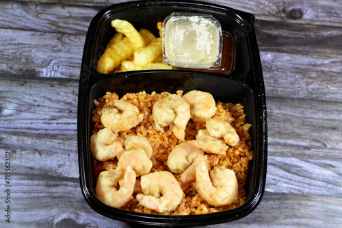 Fried shrimps on top of Sayadieh red rice full of warm Mediterranean spices, sweet caramelized onions and perfectly cooked, fried French fries with Tahini and ketchup, seafood recipe of rice shrimps photo