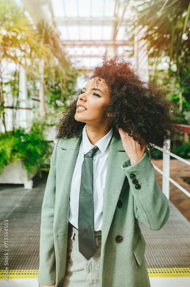 Fototapeta premium Woman with tie and afro hair smiling while touching her hair.