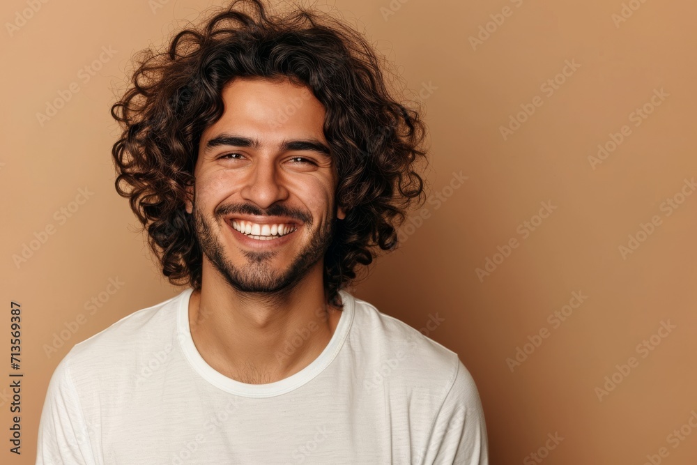Smiling man with curly hair and white T-shirt on a beige background Smiling man with curly hair and white T-shirt on a beige background