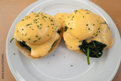 The yellow hollindaise sauce on top of two poached egg which are on a bed of spinach upon toasted english muffins. The dish is called Egg Florentine photo