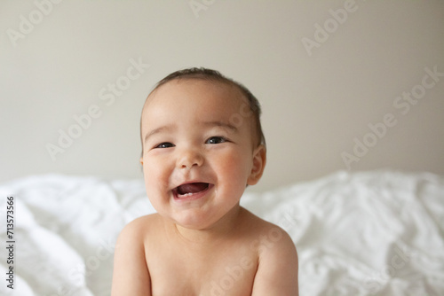 Naked baby sitting on a bed