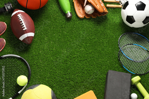 Frame made of different sports equipment on green grass  flat lay. Space for text