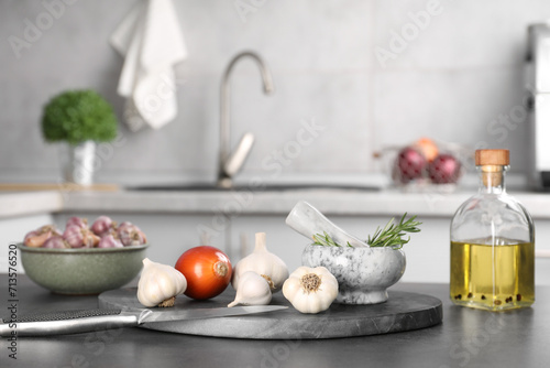 Fresh raw garlic  onion  rosemary and oil on grey table