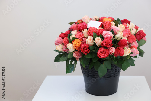 Bouquet of beautiful roses with blank card on white table against light background, space for text © New Africa