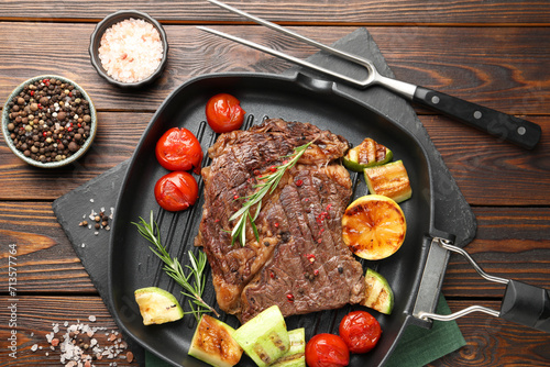 Delicious grilled beef steak and vegetables served on wooden table, flat lay