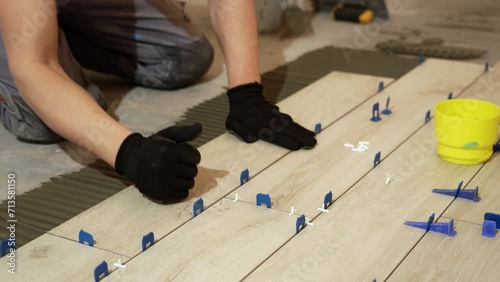 A tiler lays floor tiles on the floor. Porcelain tiles in the kitchen. A tiler is gluing tiles to the kitchen floor. A man is laying tiles on the bathroom floor.