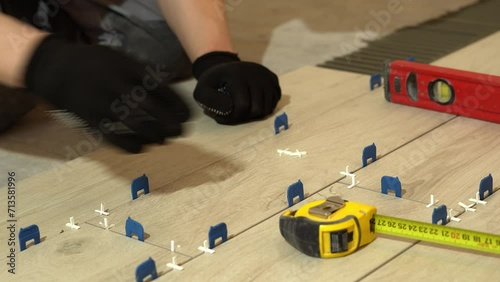 A tiler lays floor tiles on the floor. Porcelain tiles in the kitchen. A tiler is gluing tiles to the kitchen floor. A man is laying tiles on the bathroom floor.