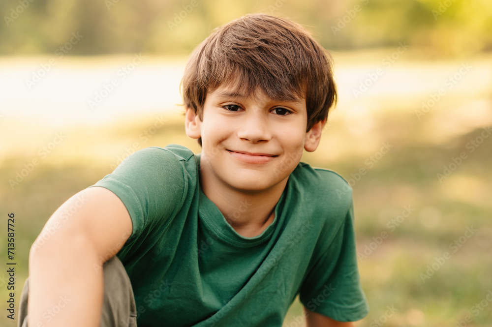 Close up portrait of a handsome teen boy smiling at the camera while sitting realxed on grass. Close up portrait of a handsome teen boy smiling at the camera while sitting realxed on grass.