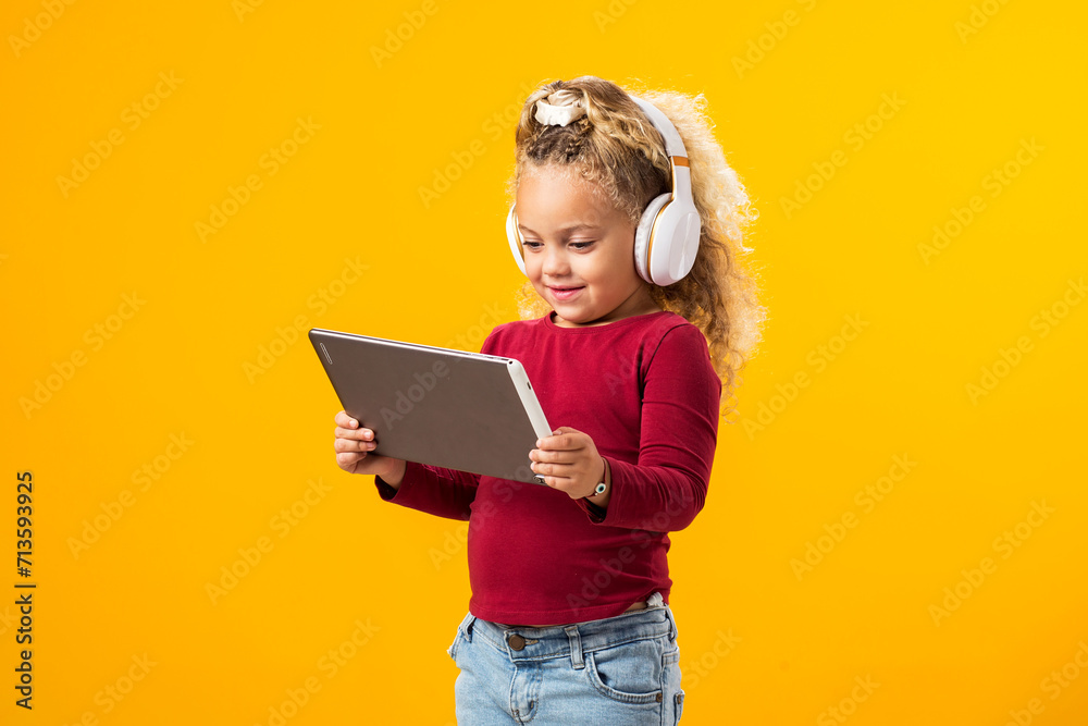 Captivating Portrait of a Joyful Kid Boy with Headphones and Tablet Immersed in Video Game Adventure. Leisure and gadget addiction concept Captivating Portrait of a Joyful Kid Boy with Headphones and Tablet Immersed in Video Game Adventure. Leisure and gadget addiction concept