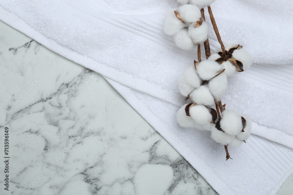 Terry towel and cotton flowers on white marble table, top view. Space for text Terry towel and cotton flowers on white marble table, top view. Space for text