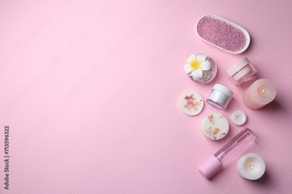 Different spa products, plumeria flower and burning candles on pink background, flat lay. Space for text Different spa products, plumeria flower and burning candles on pink background, flat lay. Space for text