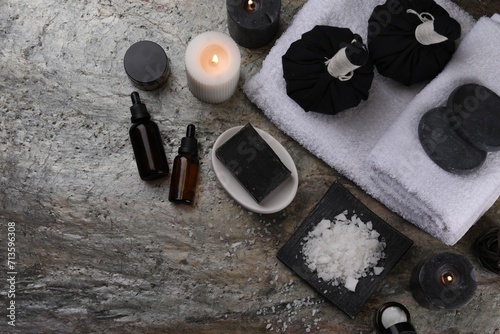 Flat lay composition with different spa products and burning candles on grey textured table. Space for text