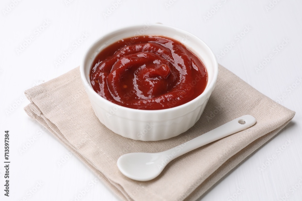 Organic ketchup in bowl and spoon on white table. Tomato sauce Organic ketchup in bowl and spoon on white table. Tomato sauce