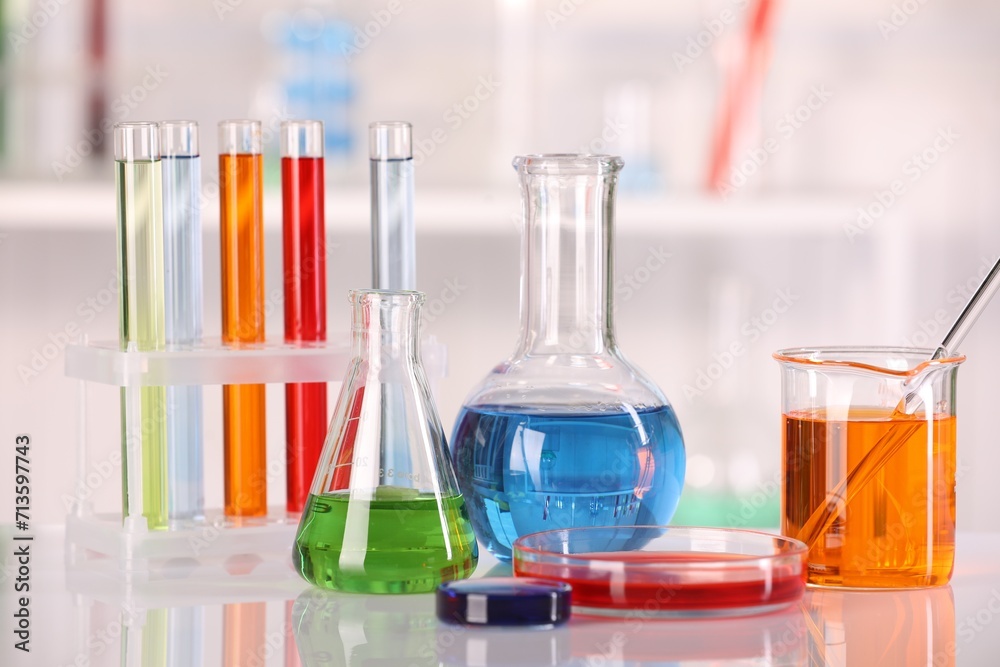 Laboratory analysis. Different glassware with liquids on white table against blurred background Laboratory analysis. Different glassware with liquids on white table against blurred background