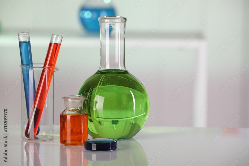 Laboratory analysis. Different glassware with liquids on white table against blurred background. Space for text Laboratory analysis. Different glassware with liquids on white table against blurred background. Space for text