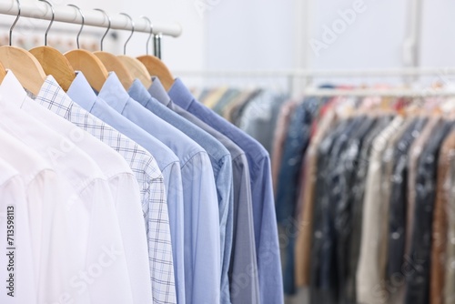 Dry-cleaning service. Many different clothes hanging on rack indoors, closeup