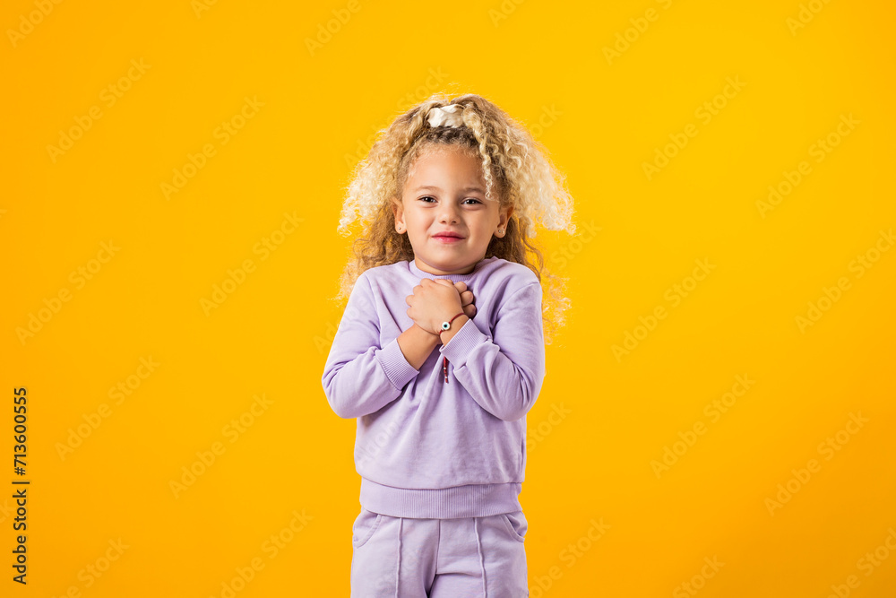 Child girl in anticipation something nice, holding palms together. Positive emotions concept