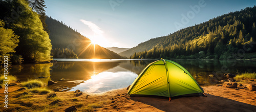 camping tent on the shores of a lake at sunrise - hiking and camping concept