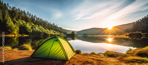 camping tent on the shores of a lake at sunrise - hiking and camping concept