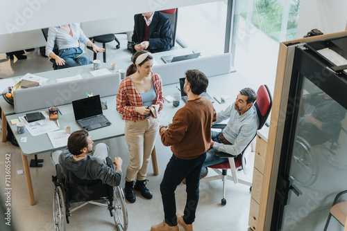 A team of colleagues are engaging in a collaborative discussion in a well-lit office environment, showcasing inclusivity with a person in a wheelchair. photo