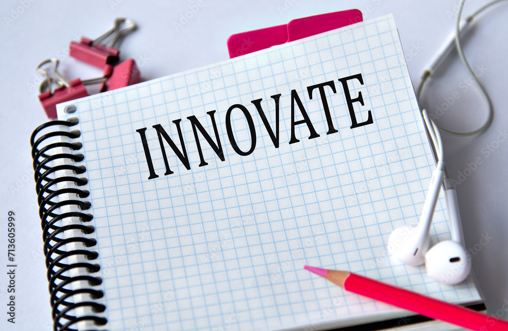 INNOVATE - word in a white notebook on a white background with headphones and a pencil INNOVATE - word in a white notebook on a white background with headphones and a pencil