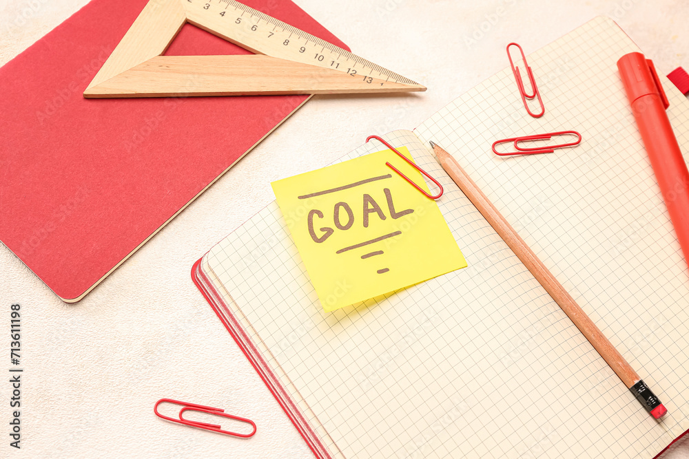 Sticky note with word GOAL and stationery on light background, closeup Sticky note with word GOAL and stationery on light background, closeup