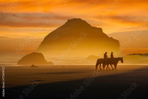 Face Rock  with horses and riders   at sunset on the southern Oregon coast at Bandon