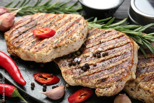 Delicious grilled pork steaks with spices on table, closeup