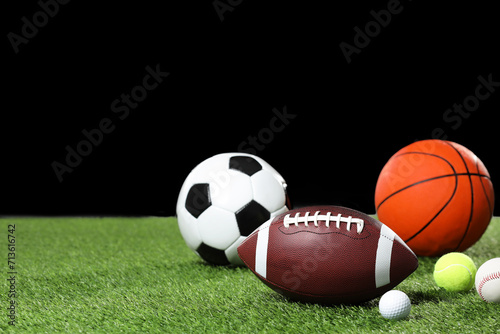 Many different sports balls on green grass against black background, space for text © New Africa