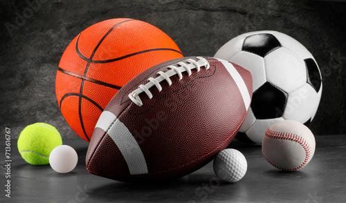 Many different sports balls on dark gray background