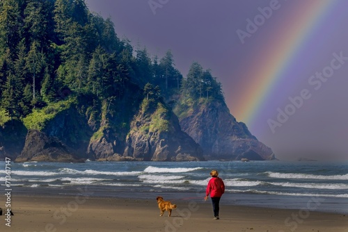 A young woman in a red sweatshirt walking a golden retreiver dog on the beach at Neskowin on the Oregon coast. photo