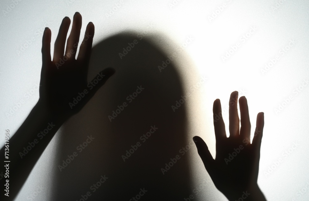 Silhouette of creepy ghost behind glass against white background
