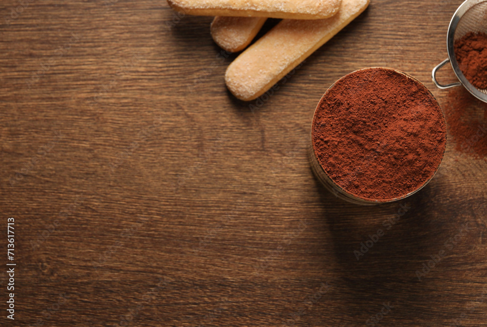 Delicious tiramisu in glass, biscuits and cocoa powder on wooden table, flat lay. Space for text Delicious tiramisu in glass, biscuits and cocoa powder on wooden table, flat lay. Space for text