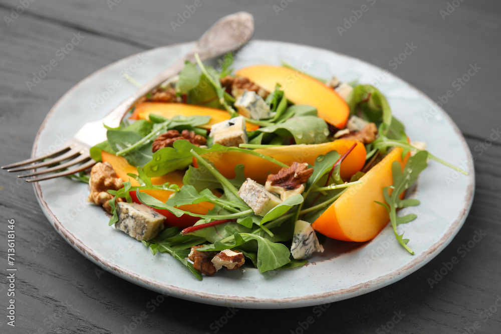 Tasty salad with persimmon, blue cheese and walnuts served on grey wooden table, closeup Tasty salad with persimmon, blue cheese and walnuts served on grey wooden table, closeup