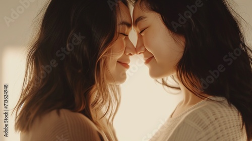 Two sisters share a close, affectionate moment, their foreheads touching gently
