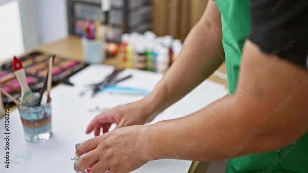 Young latin artist man creatively arranges color paint tubes on studio table, set for vibrant artistry Young latin artist man creatively arranges color paint tubes on studio table, set for vibrant artistry