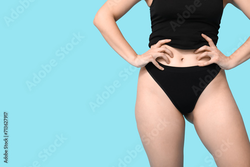 Body positive young woman in underwear on blue background, closeup
