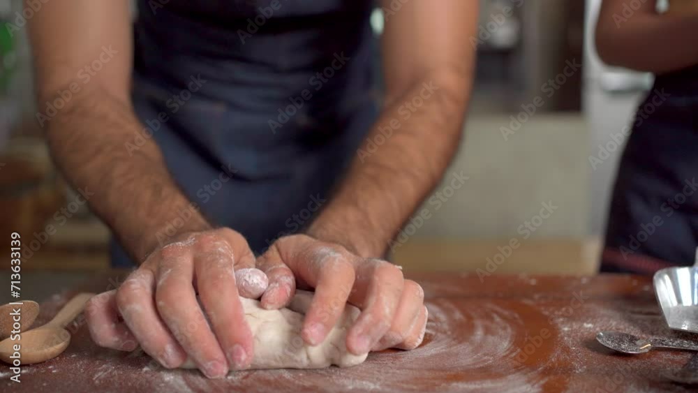 Women and men knead dough together, creating a lively, aromatic atmosphere in the kitchen as they prepare to make pizza. 