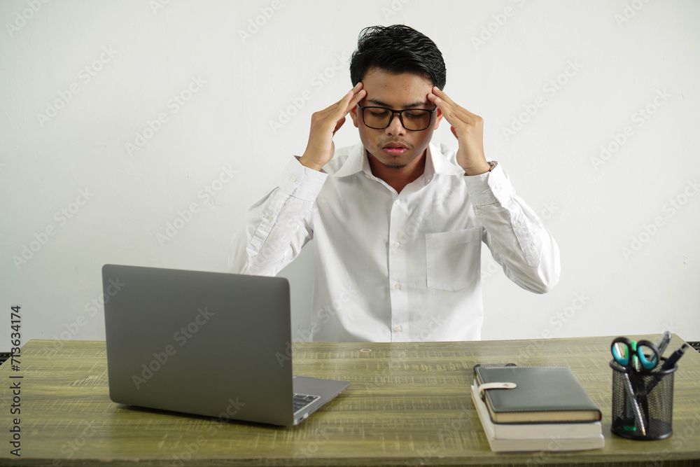 young asian businessman in a workplace with headache, wear white shirt with glasses isolated young asian businessman in a workplace with headache, wear white shirt with glasses isolated