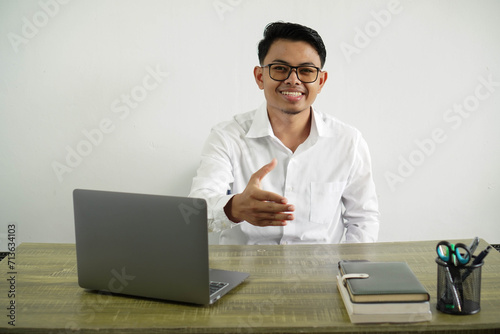 young asian businessman in a workplace shaking hands for closing a good deal, wear white shirt with glasses isolated