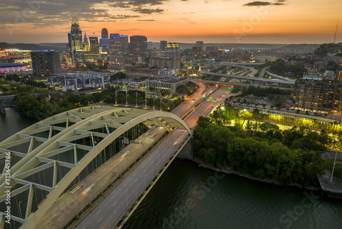 Daniel Carter Bridge in Cincinnati city, Ohio, USA with highway traffic driving cars in downtown district. American city skyline with brightly illuminated high commercial buildings at night photo