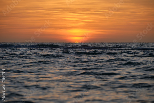 Ocean sunset. Big white sun on dramatic bright sky background  soft evening horizont over sea dark water