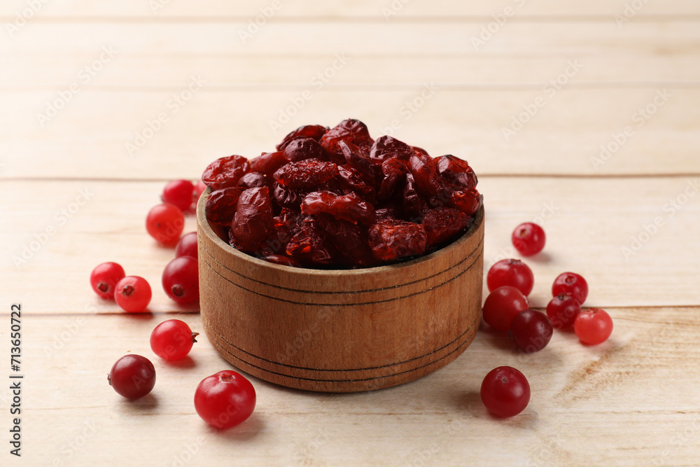 Dried cranberries in bowl and fresh berries on wooden table Dried cranberries in bowl and fresh berries on wooden table