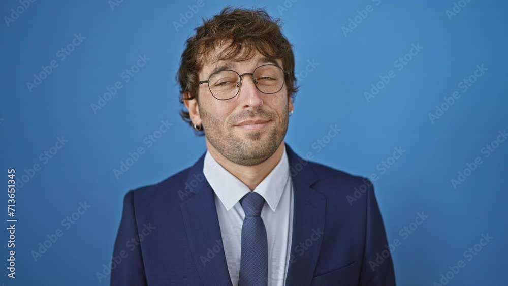 Cheerful young man, confident and thinking, in fashionable business suit, looking away to the side with a happy, smiling face. over blue, isolated background, he's a smart look.