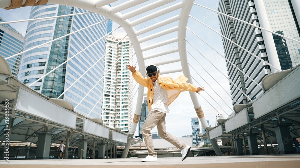 Stylish asian man perform hiphop dancing with low angle camera. Break dancer walking up the stair while listening music from headphone and dancing together at city. Outdoor sport 2024. Sprightly.